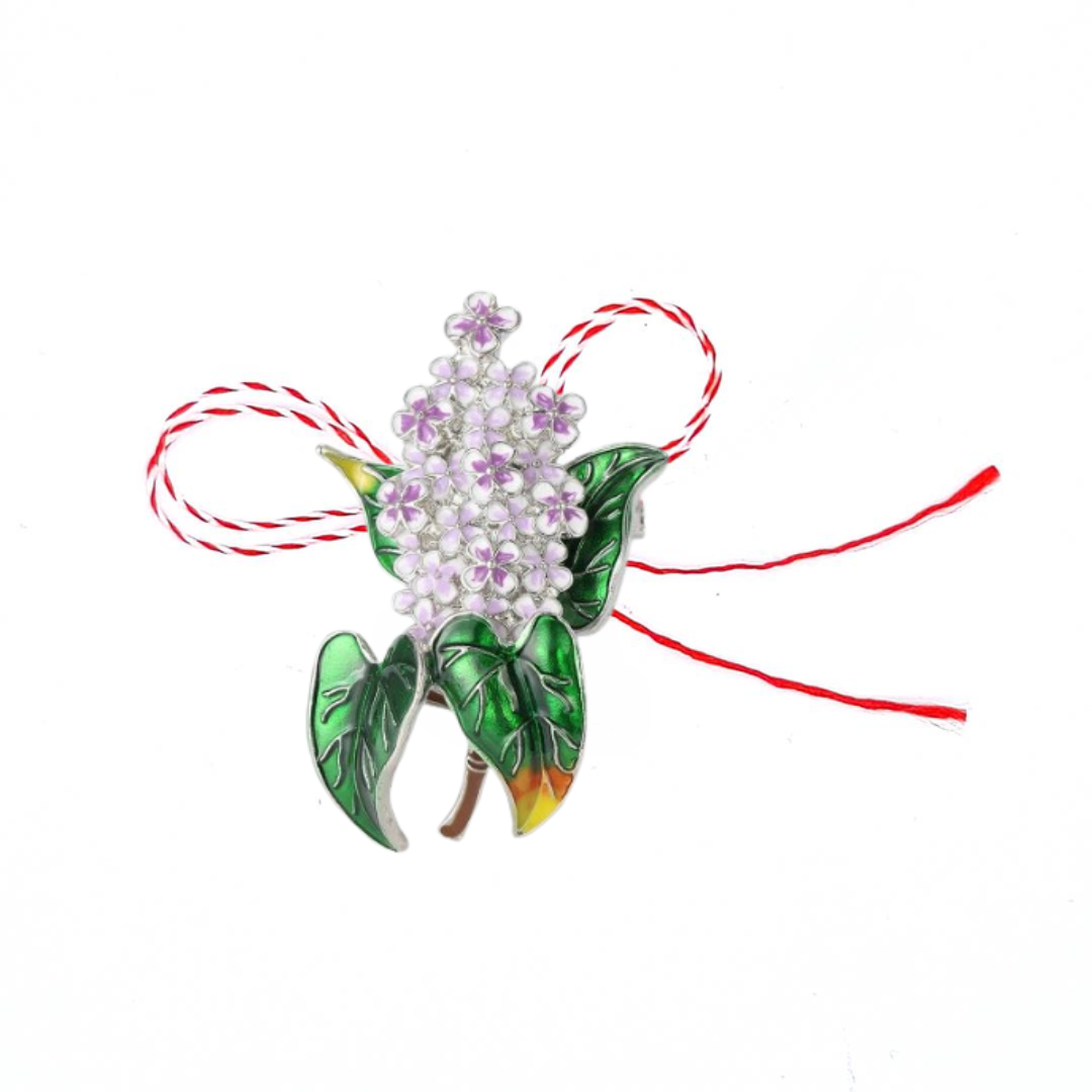 Lilac Flower Martisor Brooch on a white background, featuring delicate purple blossoms and vibrant green leaves with golden accents, symbolising spring and renewal, paired with the traditional red and white Martisor bow.