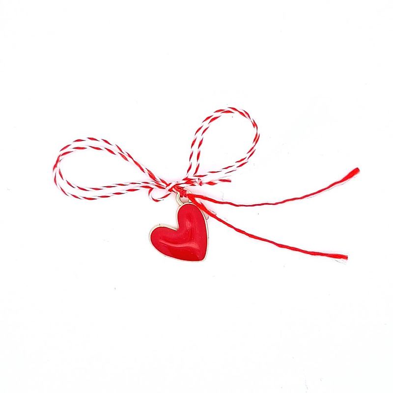 Close-up of gold-plated red enamel heart charm with traditional Mărțișor red and white string