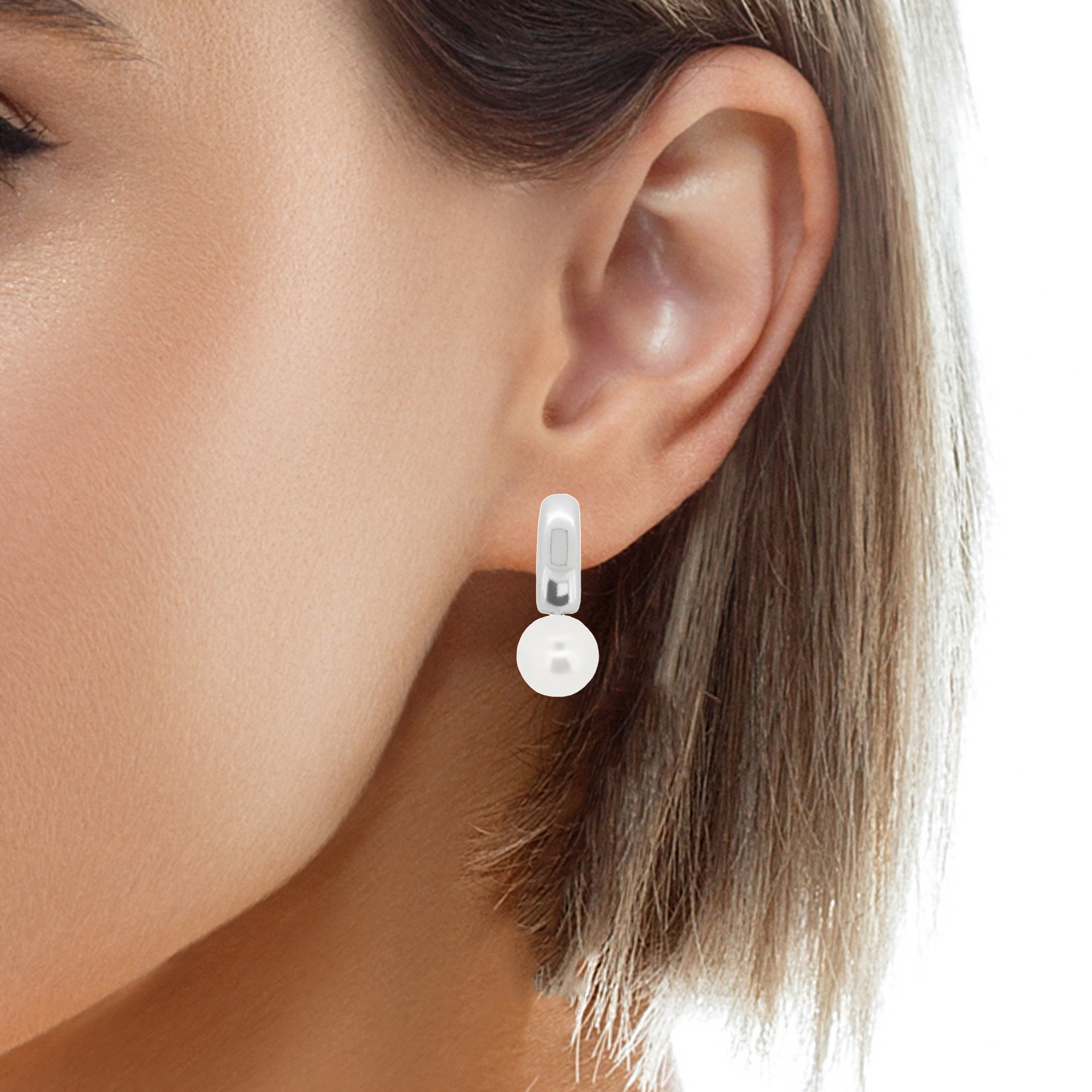 Woman wearing 8mm pearl huggie hoop earrings in sterling silver, showcasing the elegant and versatile design.