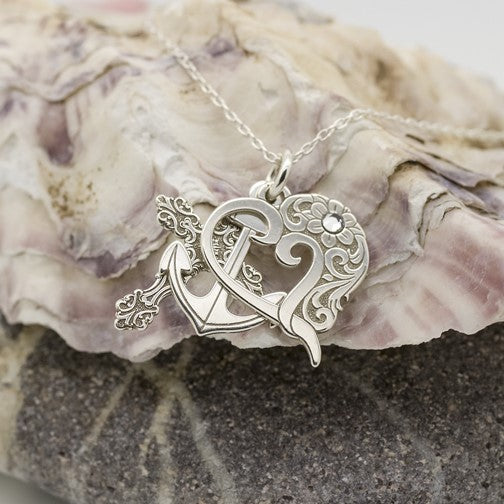 A triple pendant necklace with a silver cross, heart and anchor