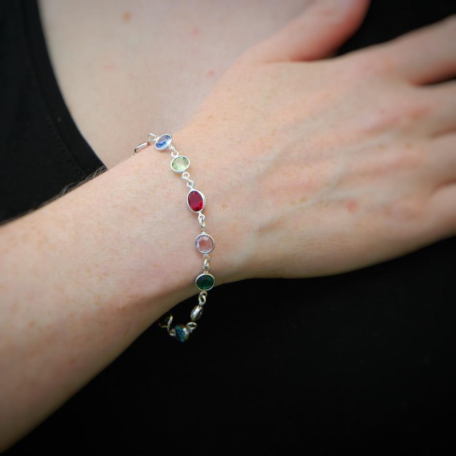 Woman displaying a multicoloured crystal bracelet with 12 birthstones, made in Ireland. Sterling Silver Family Link Bracelet with Personalised Birthstones