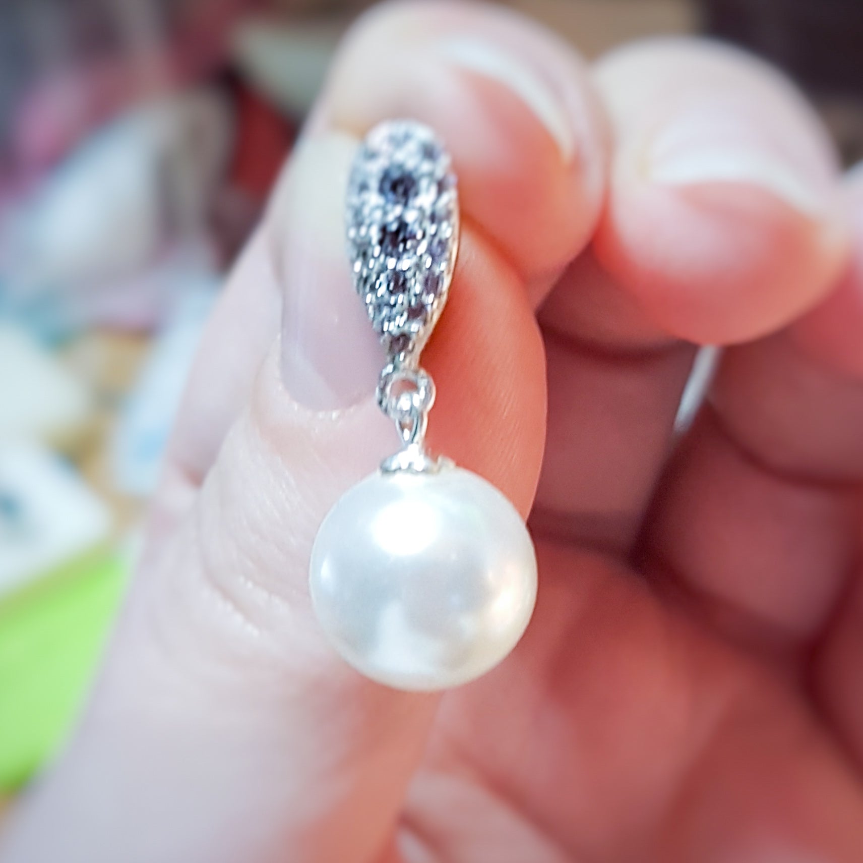 Hand holding Elegant Pearl Drop Earring in Sterling Silver featuring a 12mm white pearl and Austrian crystal teardrop design made in Ireland